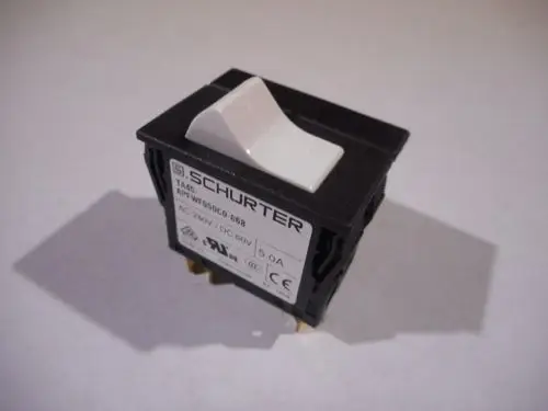 Schwarzer Schalter von Remeha mit einer weißen Betätigung, ausgestattet mit Anschlussklemmen auf der Unterseite und einem Typenschild mit technischen Angaben.